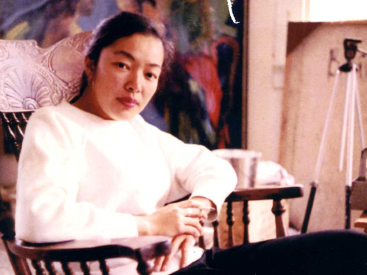 Portrait of a woman in a white sweater sitting in a chair.