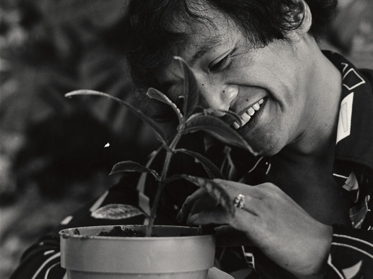 A man smiles fondly at a plant.