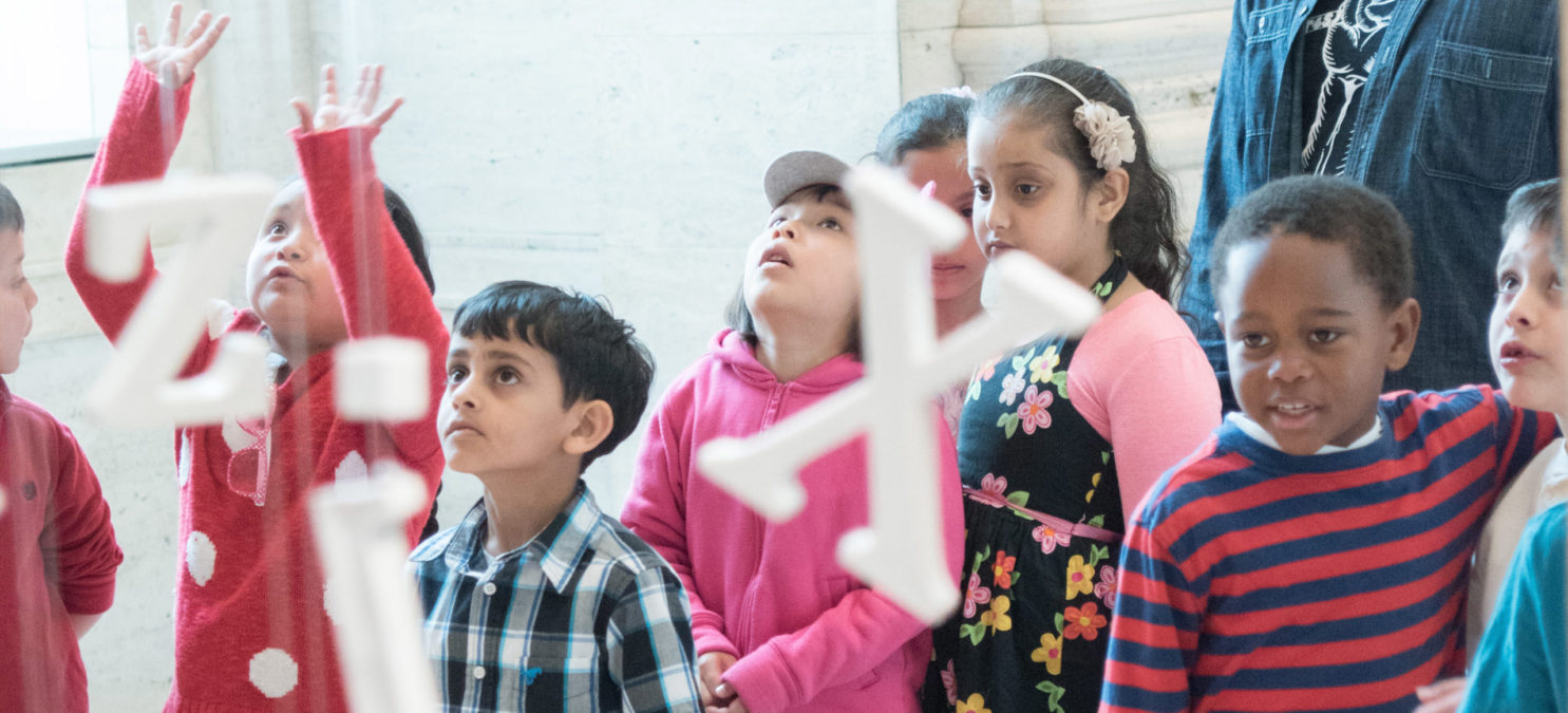 Small children look at an art installation.